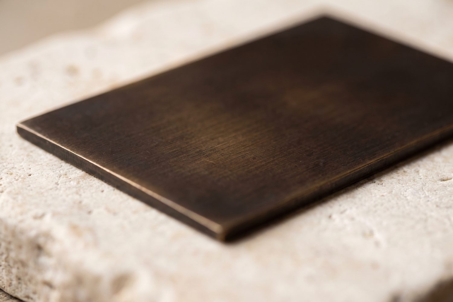 Blackened brass sample plate macro, warm brown-black