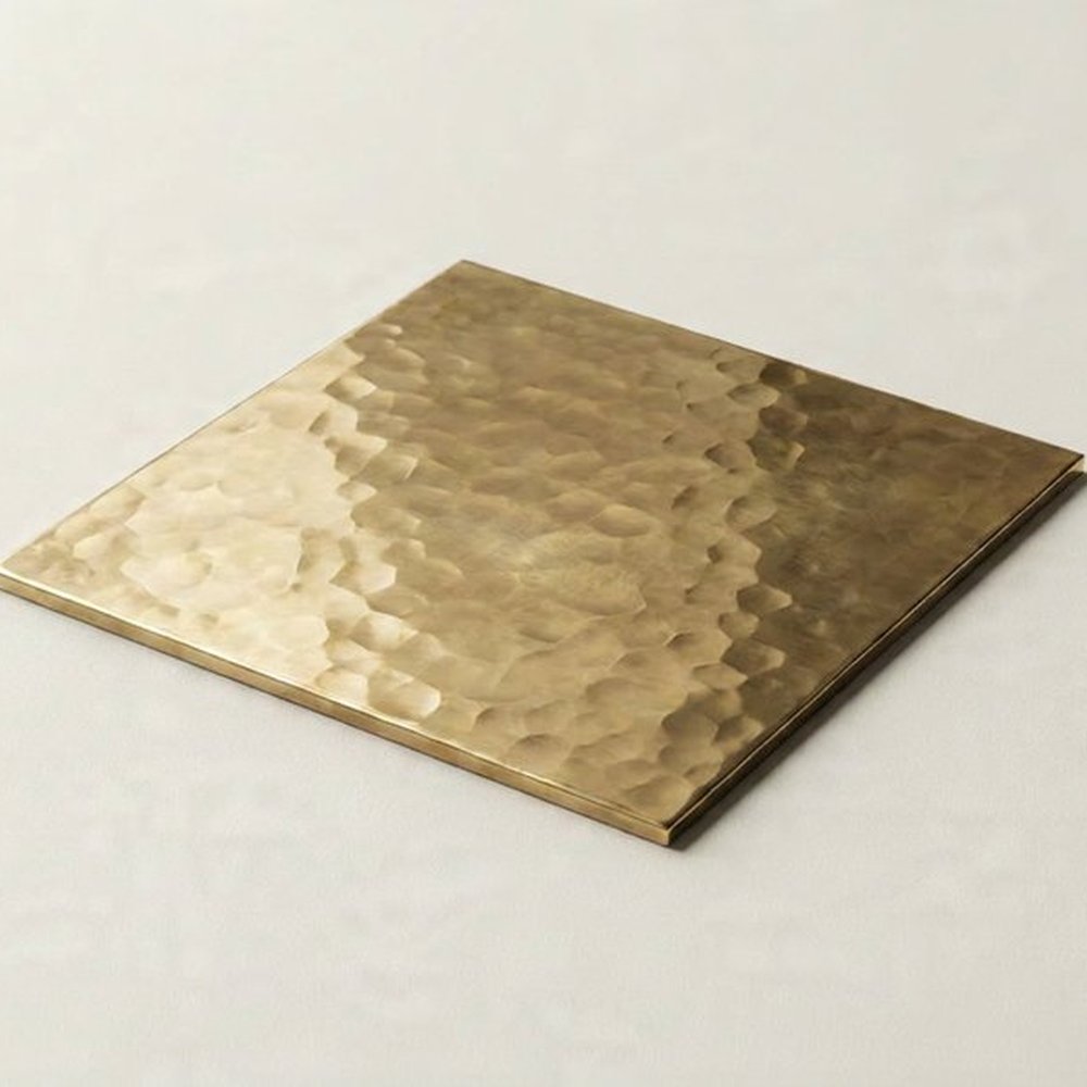 Hammered brass sample plate, light caught across a worked surface