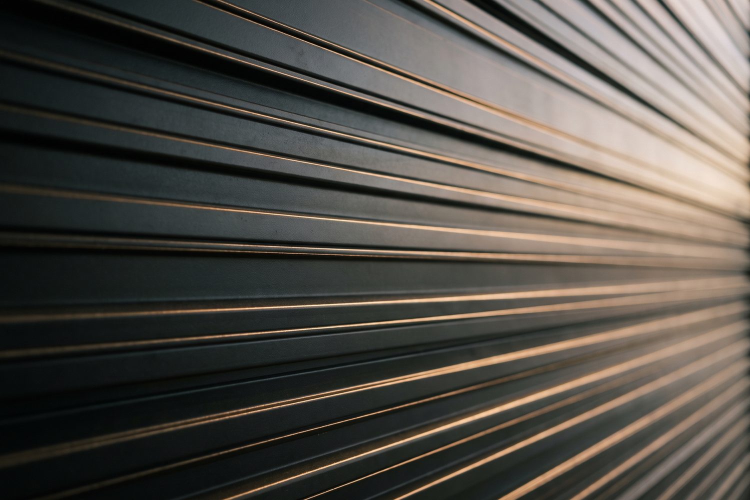 Blackened ribbed metal panel catching low light