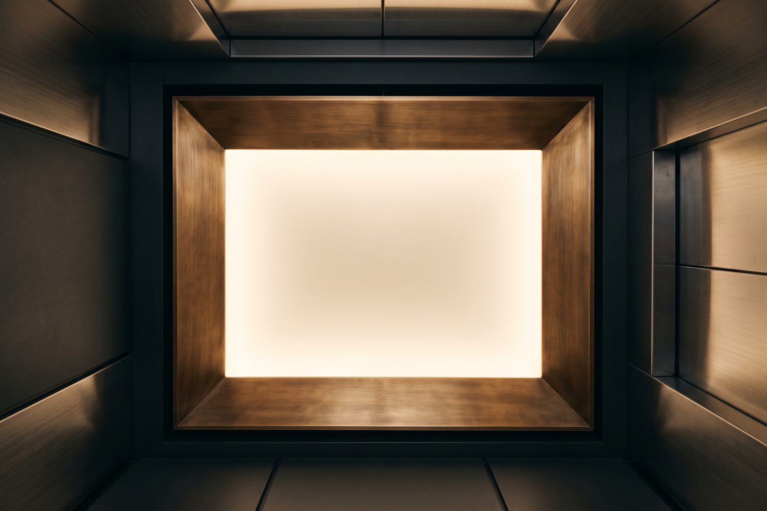 Backlit lift ceiling framed in brushed bronze