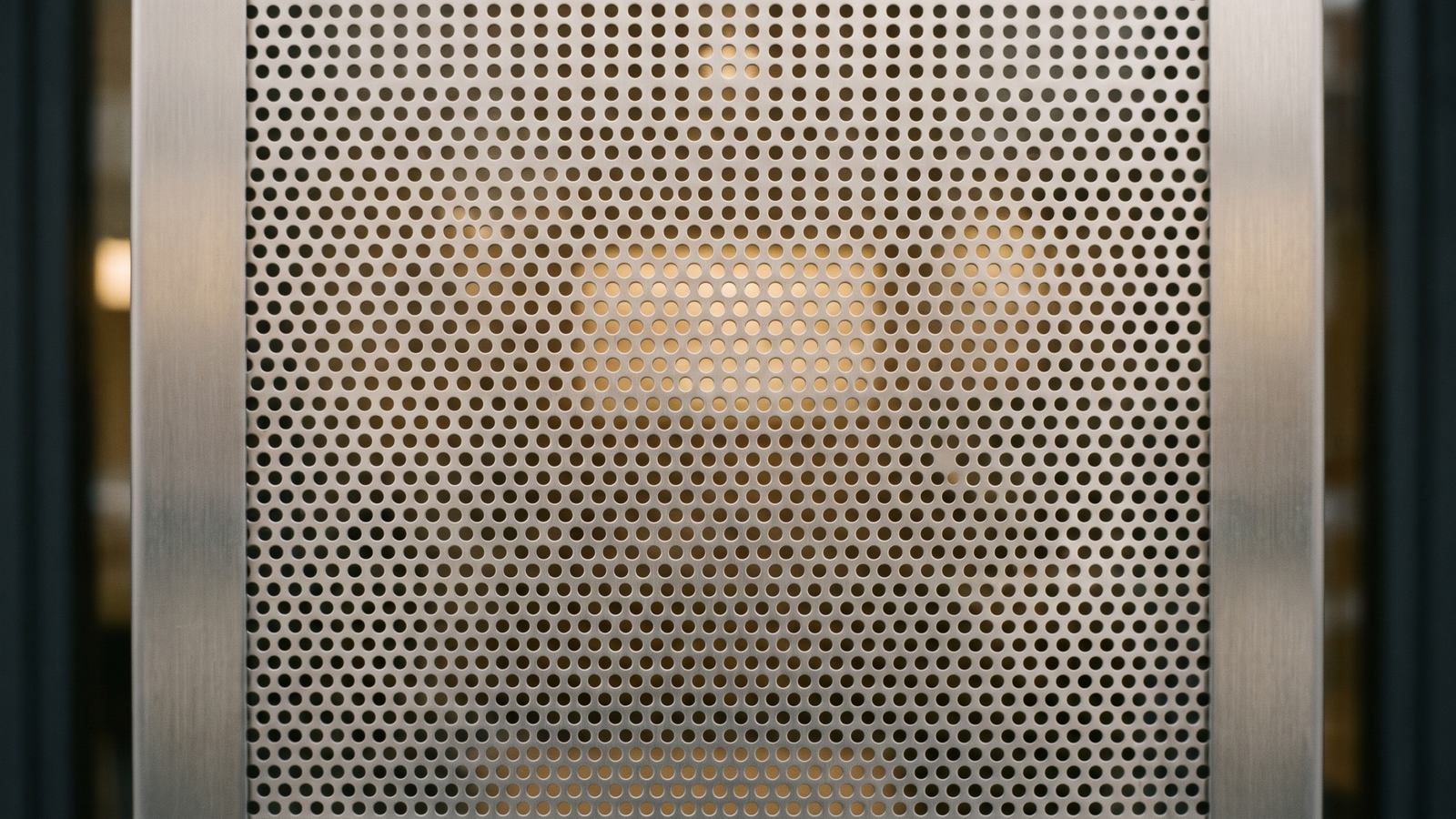 Flat perforated stainless steel panel in soft daylight